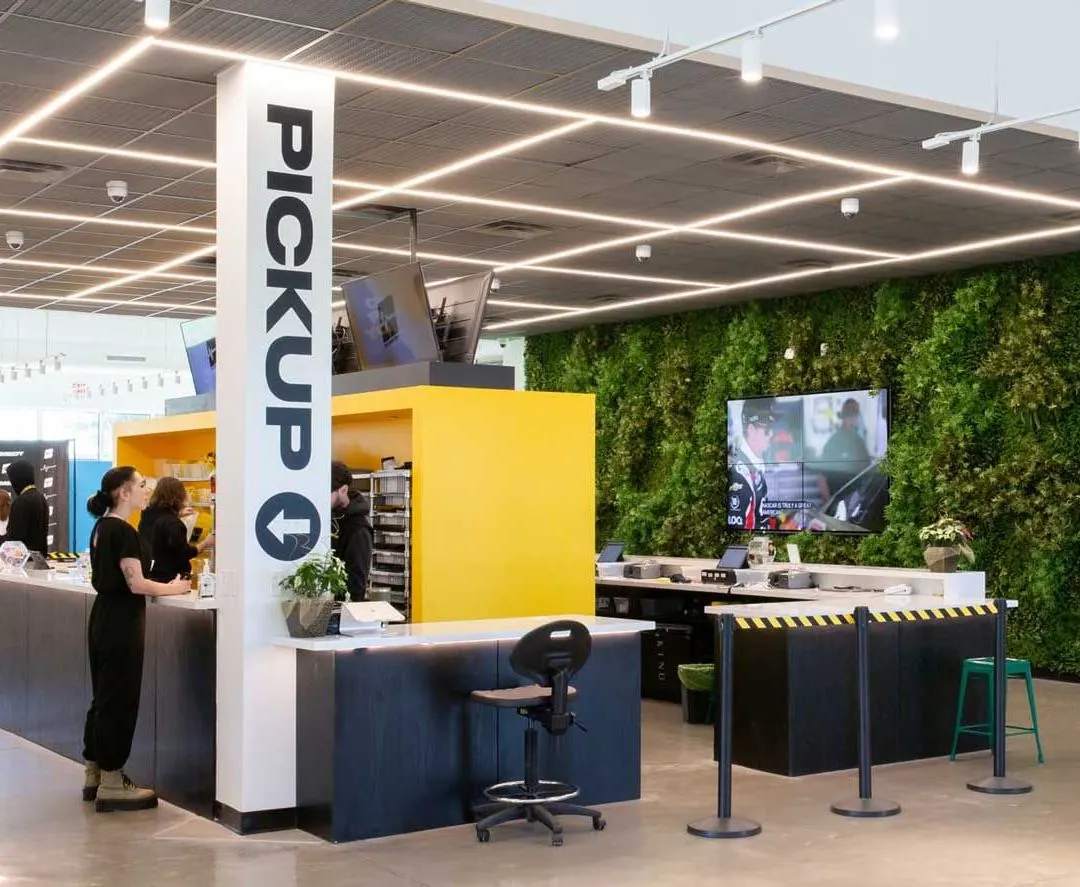 Bright cannabis dispensary interior with pickup counter and green plant wall